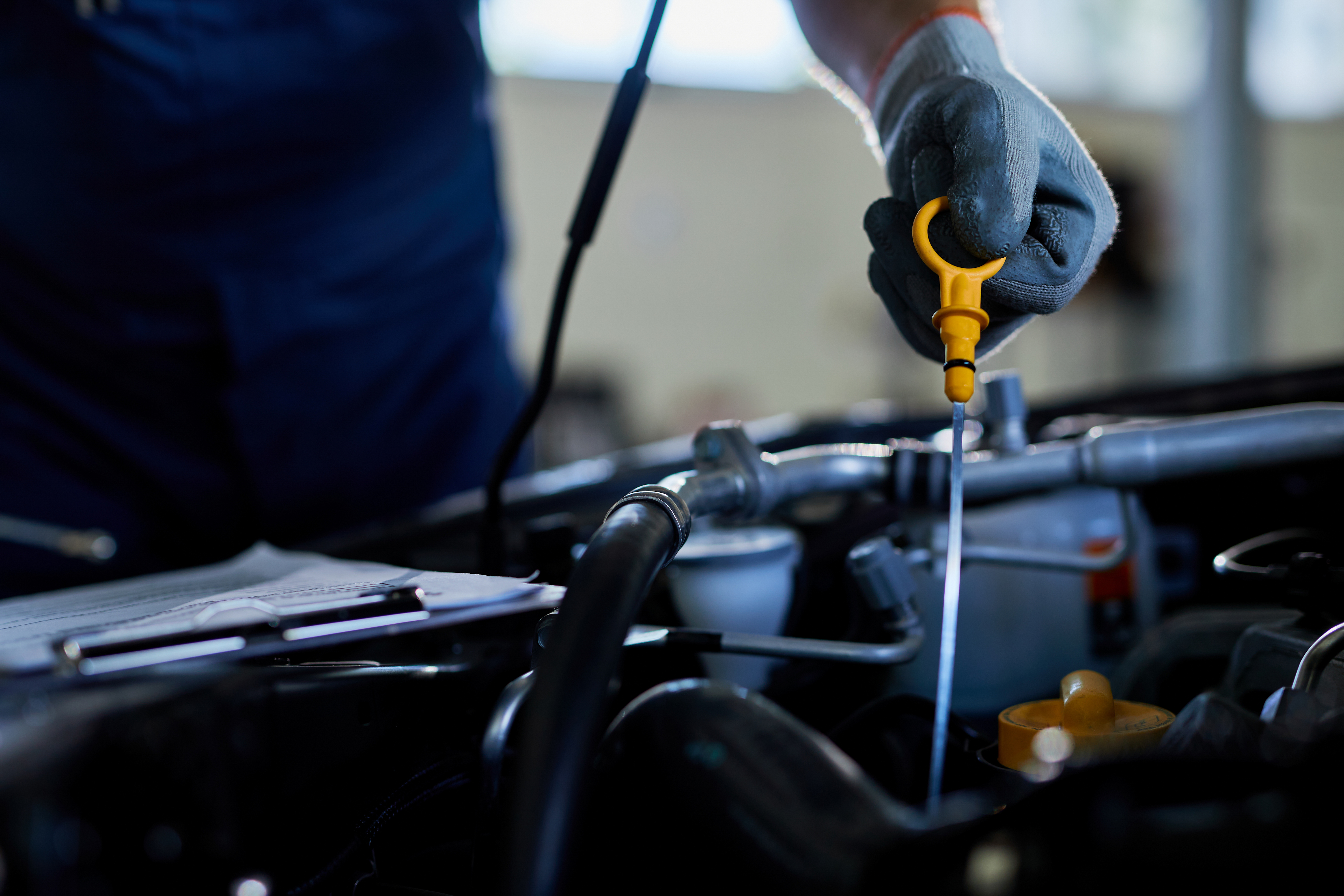 Close-up of a auto repairman checking car oil in a workshop. Close-up of a mechanic checking car oil in auto repair shop.